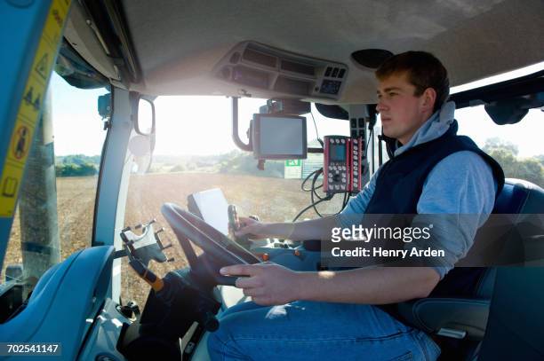 young man driving tractor using global positioning system - agriculteur conducteur tracteur photos et images de collection