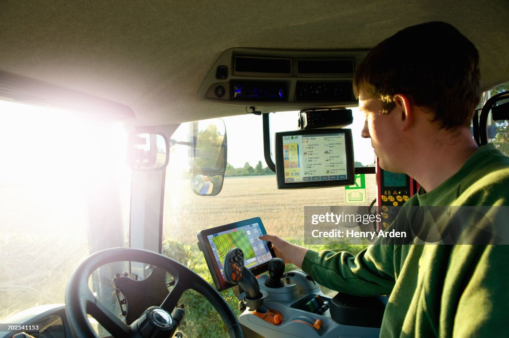 Young man driving tractor using touchscreen on global positioning system