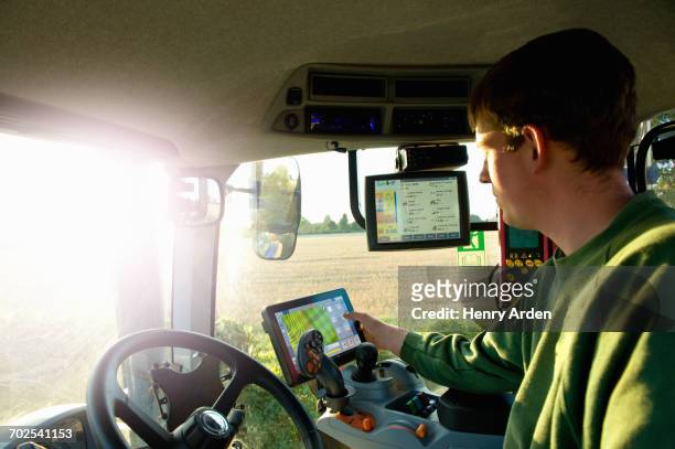 Young man driving tractor using touchscreen on global positioning system