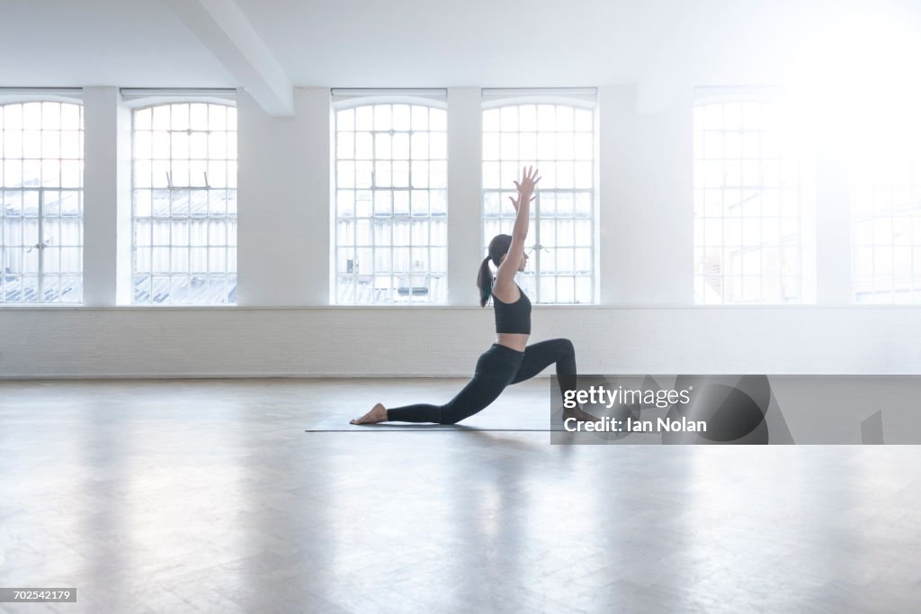 Side view of woman in dance studio in yoga position