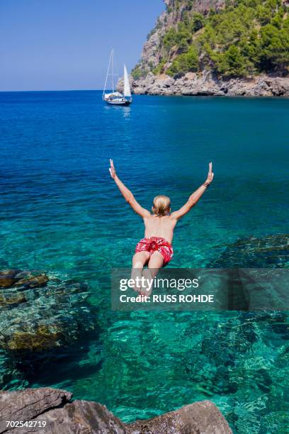 rear view of young man diving into sea, cala tuent, majorca, spain - sierra de tramuntana stock pictures, royalty-free photos & images