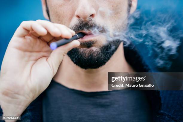 portrait of man smoking an electronic cigarette - vaping imagens e fotografias de stock