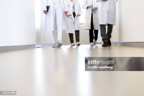 neck down view of male and female doctors walking in hospital corridor - junior doctor stock pictures, royalty-free photos & images