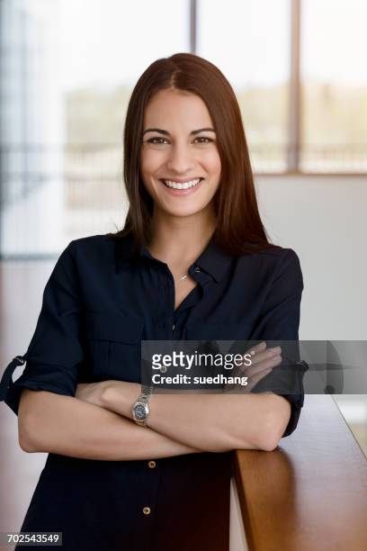 portrait of young businesswoman with arms folded in office corridor - black blouse fotografías e imágenes de stock