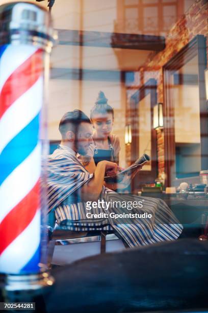 hairdresser showing customer magazine - barber pole stock pictures, royalty-free photos & images