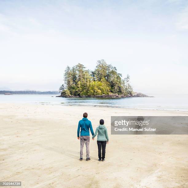 couple looking out at island from long beach, pacific rim national park, vancouver island, british columbia, canada - pacific rim national park reserve stock pictures, royalty-free photos & images