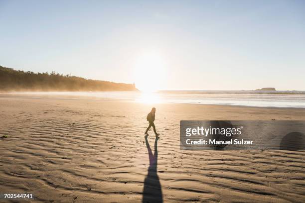 woman strolling on long beach at sunrise, pacific rim national park, vancouver island, british columbia, canada - pacific rim imagens e fotografias de stock