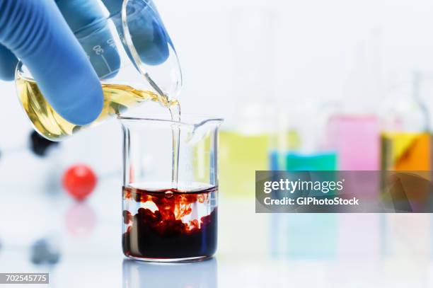 scientist pouring iron chloride into beaker of potassium thiocyanate - chemical reaction stock pictures, royalty-free photos & images