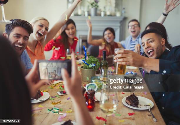 woman with camera phone photographing playful friends throwing confetti at restaurant table - throwing cake stock pictures, royalty-free photos & images
