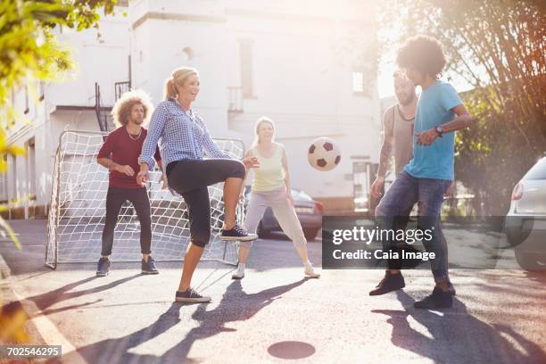 friends playing soccer in sunny summer street - mujeres de mediana edad fotografías e imágenes de stock