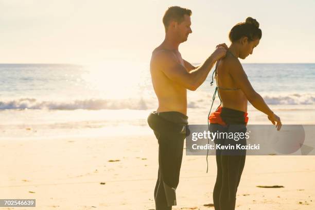 man helping girlfriend put on wetsuit at newport beach, california, usa - surfer wetsuit stock pictures, royalty-free photos & images