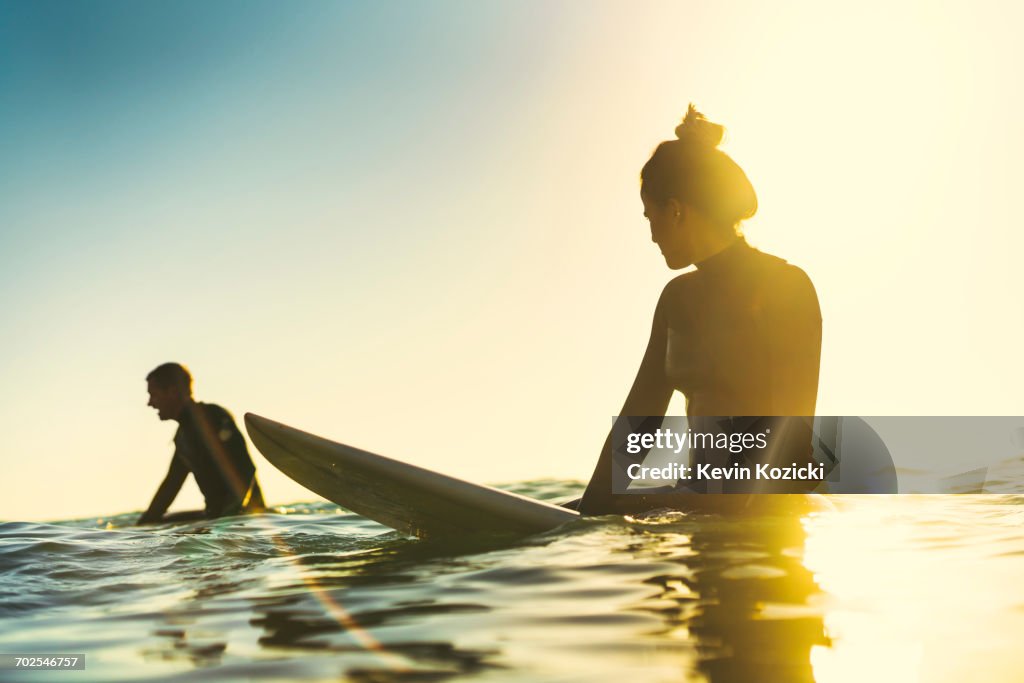 Surfing couple wading in sea, Newport Beach, California, USA