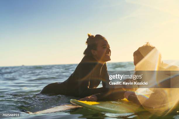 surfing couple leaning on surfboards in sea, newport beach, california, usa - newport beach california stockfoto's en -beelden