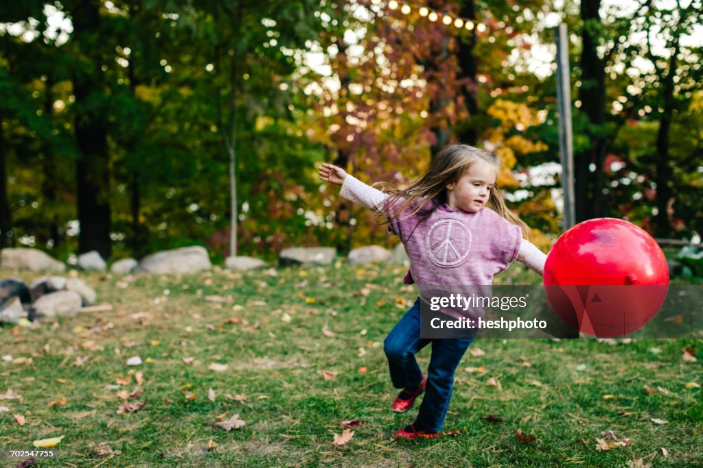 Girl playing with red balloon in garden