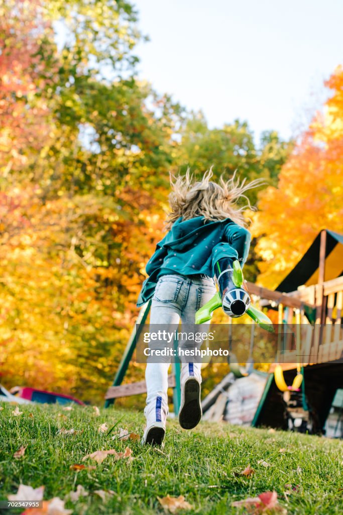 Rear view of girl running with toy rocket in garden