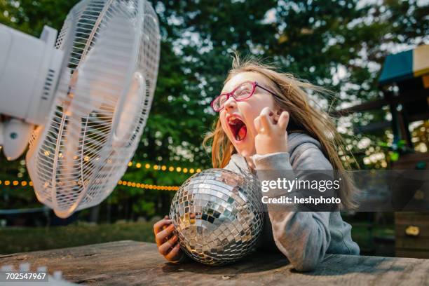 girl screaming in front of windy electric fan at garden table - table fan stock pictures, royalty-free photos & images