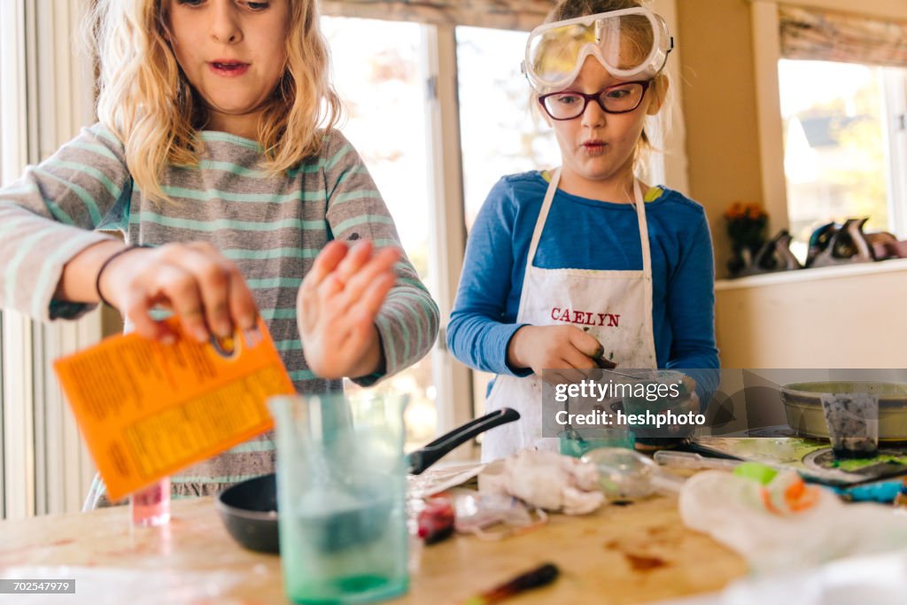 Two girls doing science experiment, pouring packet into frying pan