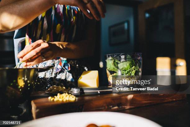 woman preparing pasta with basil, pine nuts - pesto stock-fotos und bilder