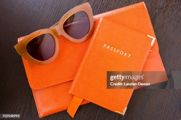 overhead view of orange purse, passport and sunglasses - bolso naranja fotografías e imágenes de stock