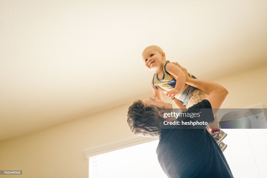 Father holding young son in air, low angle view