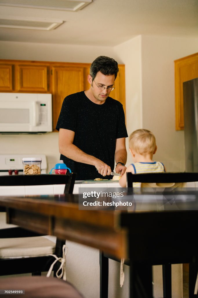 Father and young son at home, father preparing food