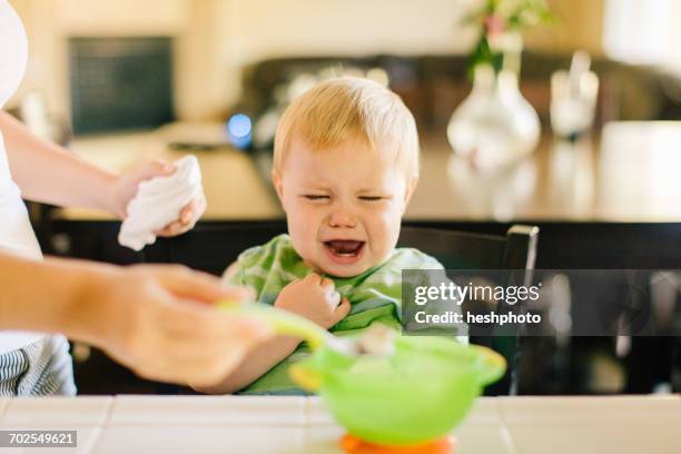 mother helping young son eat breakfast, son crying, mid section - angry parent mealtime stock pictures, royalty-free photos & images