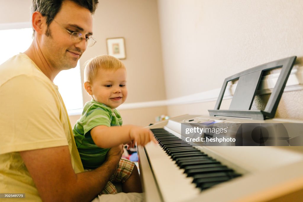 Father and young son playing musical keyboard together