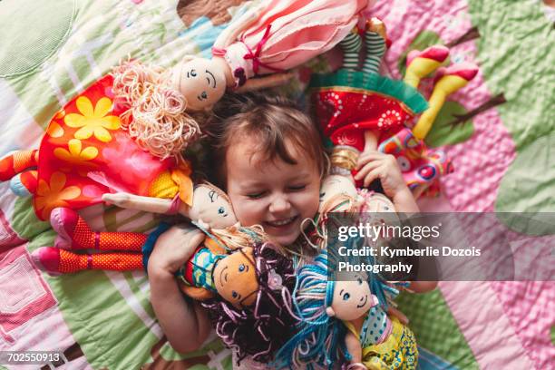 girl lying on bed surrounded by rag dolls - surrounding stock-fotos und bilder