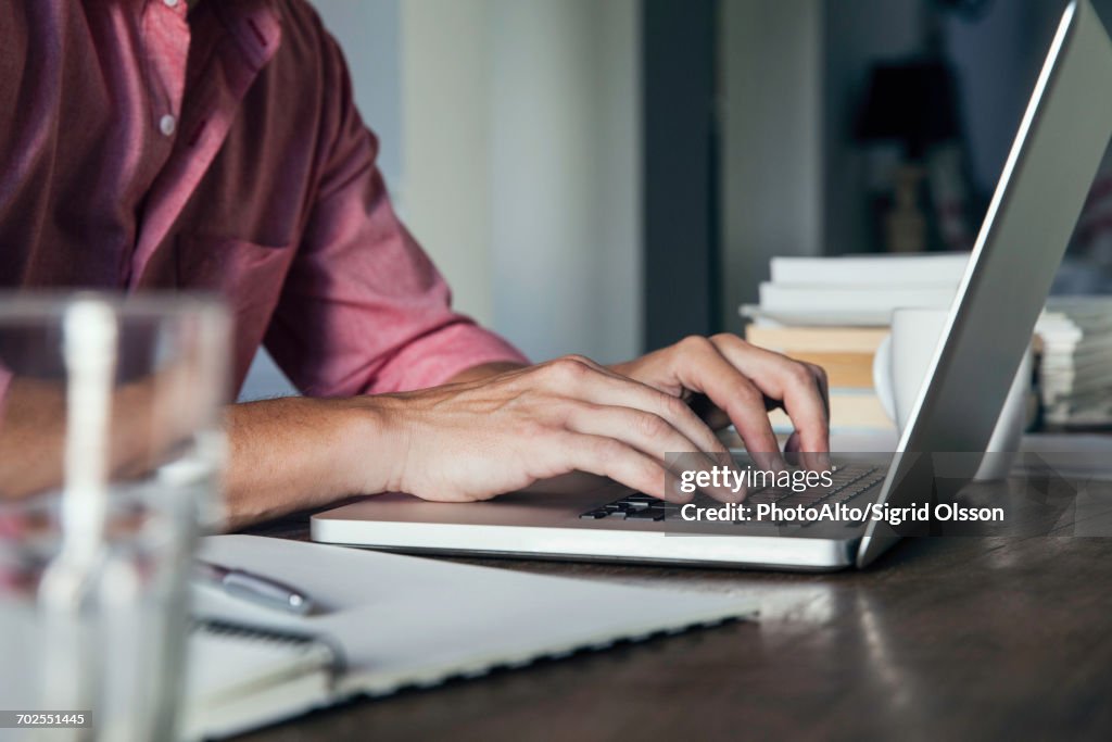 Man typing on laptop computer, cropped