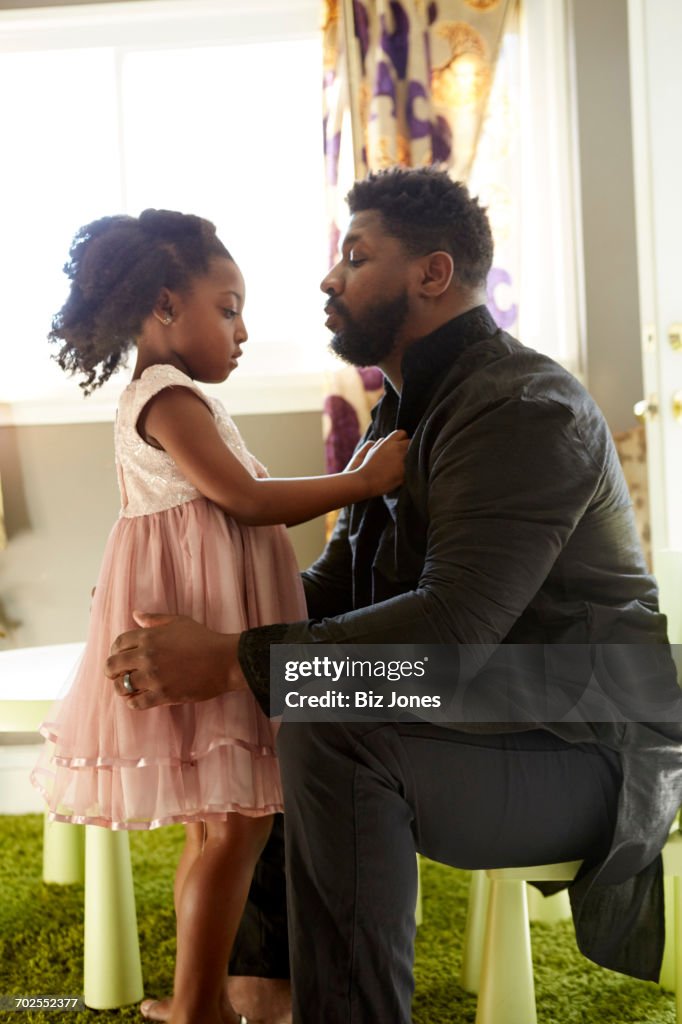 Girl buttoning fathers shirt at home