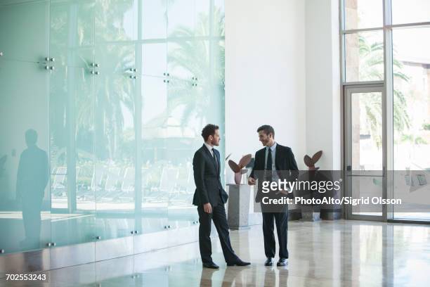 business associates talking in office lobby - geschäftskleidung stock-fotos und bilder