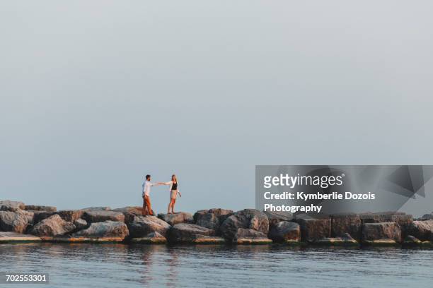 distant view of couple holding hands on boulder wall, lake ontario, toronto, canada - toronto summer stock pictures, royalty-free photos & images