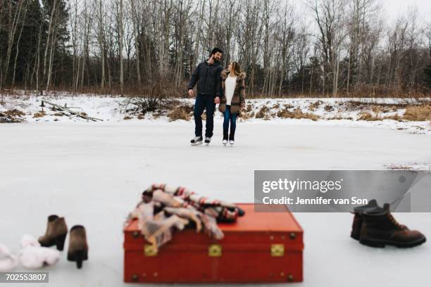 red suitcase, boots, shawl, couple skating in background, whitby, ontario, canada - whitby ontario canada stock pictures, royalty-free photos & images