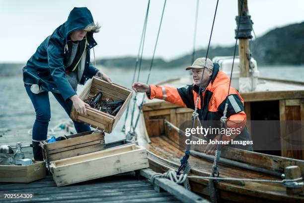 people unloading boat - visindustrie stockfoto's en -beelden