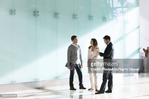 business associates chatting in office corridor - kleine personengruppe stock-fotos und bilder