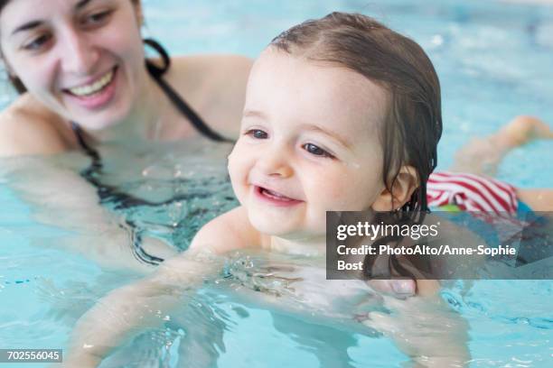 little girl learning to swim with help of parent - mother and baby taking a bath stock pictures, royalty-free photos & images