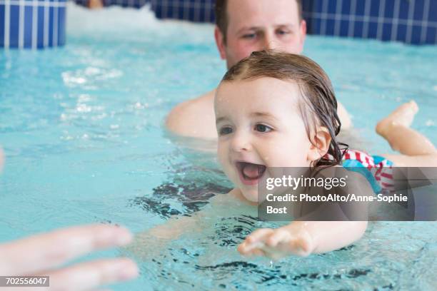 little girl learning to swim with help of parent - baby swim imagens e fotografias de stock