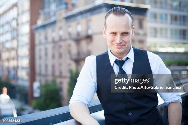 businessman on balcony, smiling, portrait - teruggekamd haar stockfoto's en -beelden