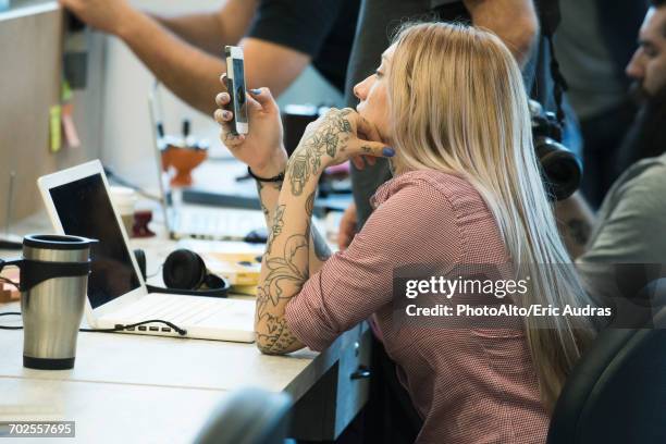 young woman staring at smartphone in office - perder el tiempo fotografías e imágenes de stock