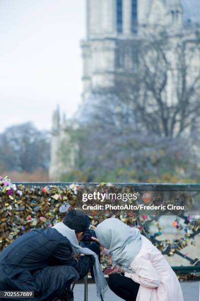 couple photographing love locks at pont des arts, paris, france - pont des arts padlocks stock pictures, royalty-free photos & images