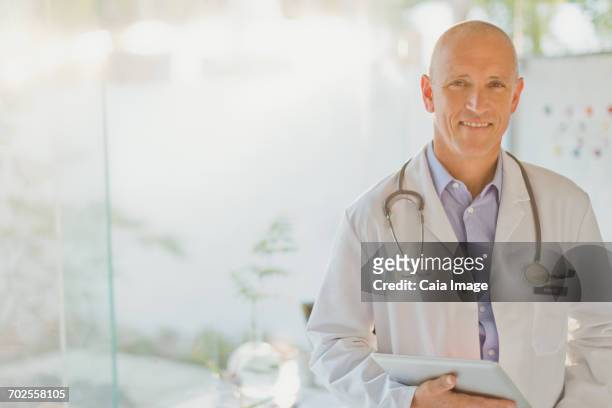 portrait confident male doctor with digital tablet - caiaimage stock-fotos und bilder