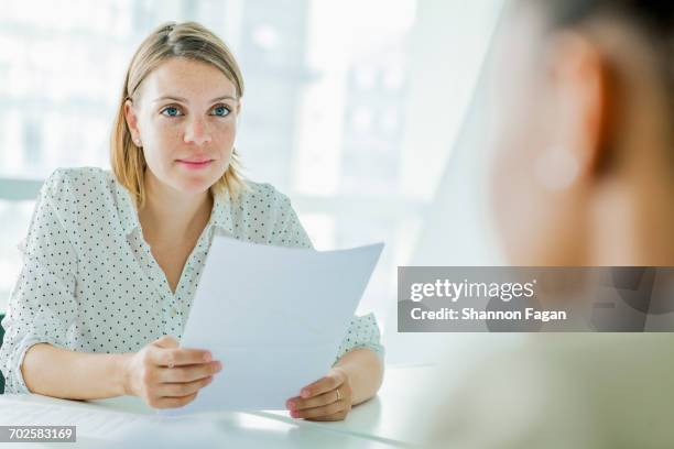 woman reviewing resume report at conference table - currículum vitae fotografías e imágenes de stock