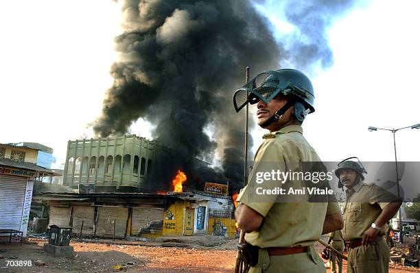 Indian state police watch a Muslim owned shop burn March 1, 2002 in Ahmadabad, India, two days after a Muslim mob attacked a train, killing 58 people...