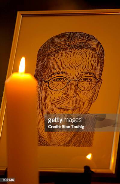 Candle flickers next to a portrait of Wall Street Journal reporter Daniel Pearl March 5, 2002 at a memorial service in St Brides Church in London....