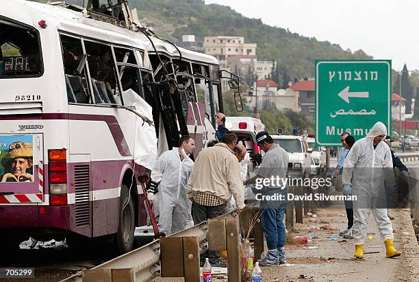 Israeli police investigators inspect a passenger bus destroyed by a Palestinian suicide bomber March 20 who blew himself up on the bus filled with...
