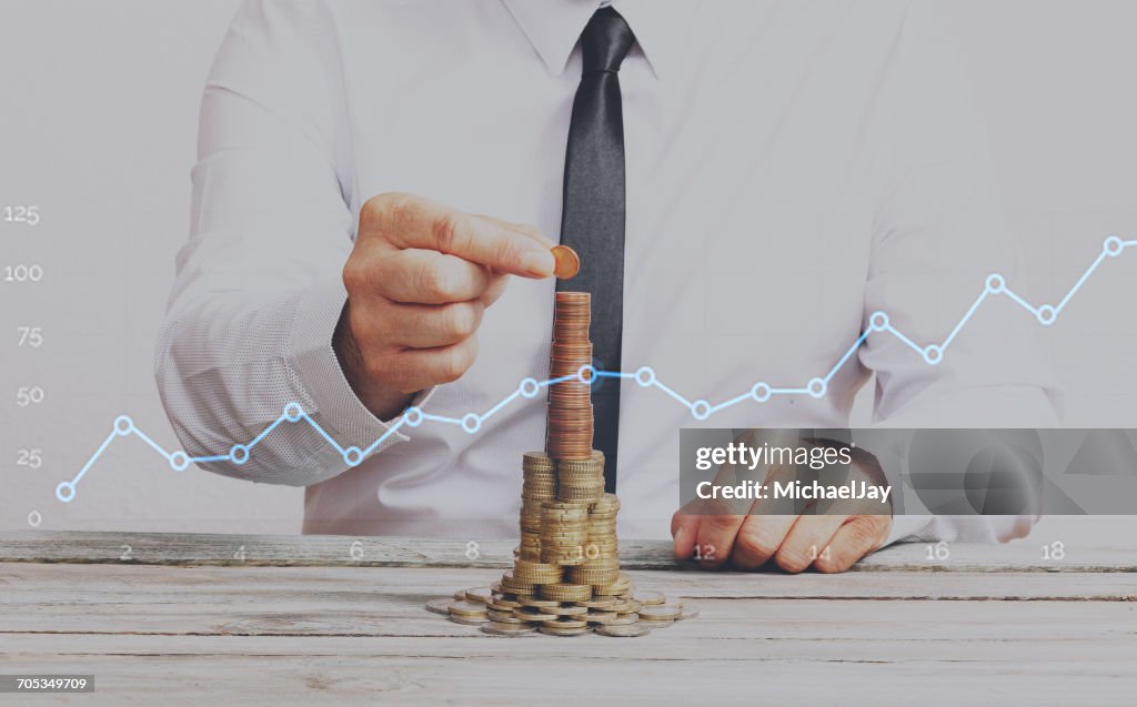 Double Exposure Of Businessman Arranging Coins And Line Graph