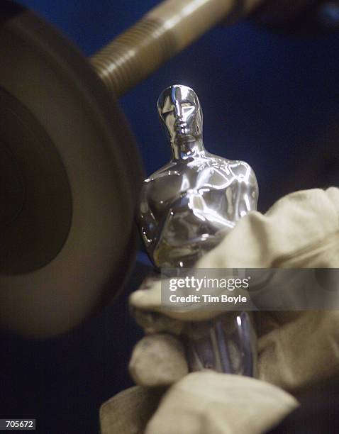 The gloved hands of Jose Irizarry buffs and polishes an Oscar statue made for the Academy Awards prior to its plating at the R.S. Owens manufacturing...
