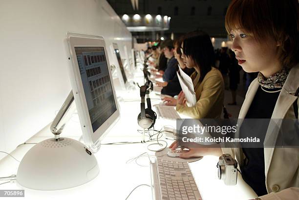 Visitors test out the new Apple iMac computer and iPod on the opening day of the Macworld Expo March 20, 2002 in Tokyo, Japan. The annual conference...