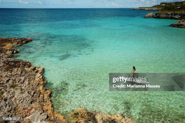 a woman paddle boards in the caribbean - bahamian women stock pictures, royalty-free photos & images