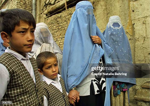 Afghan boys wait with their burqa-clad mother to start their first day of the official school year March 23, 2002 at the Amir Dost Mohammad Khan...